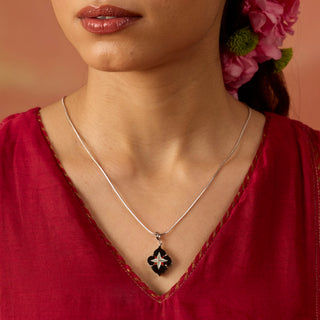 Model wearing Mehrab noir charm Mother of pearl and Red Carnelian floral inlay on black marble styled with Silver chain.